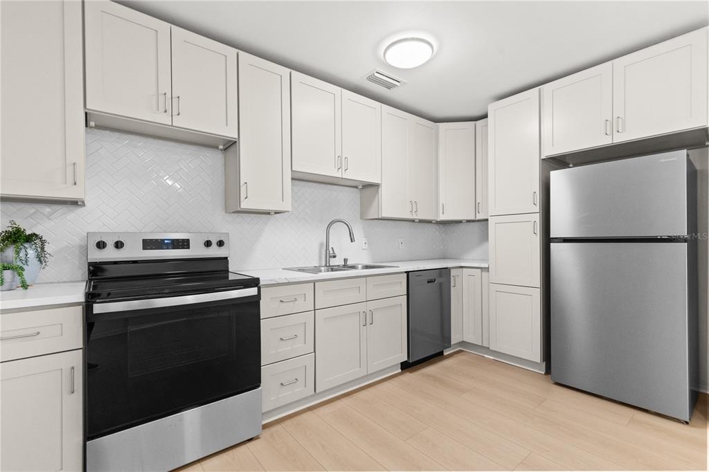 A kitchen features light gray cabinets, stainless steel appliances, white countertops, and a herringbone backsplash — 3663 22ND AVENUE N, ST PETERSBURG, FL