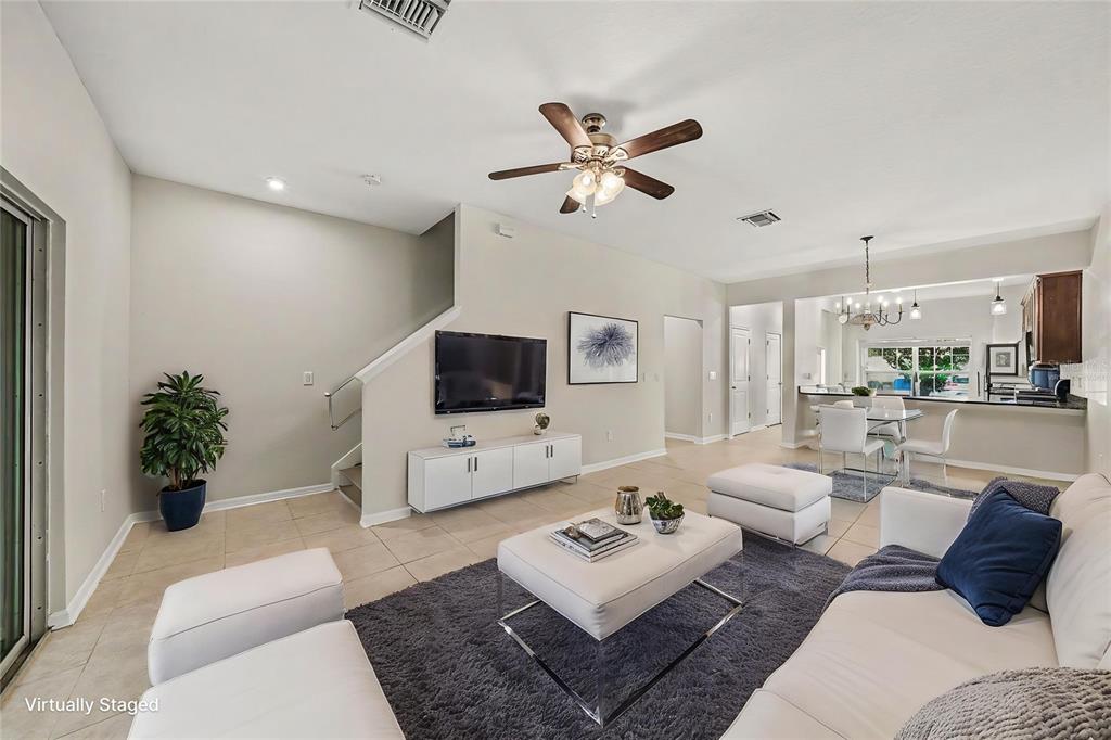 A living room features tile flooring, a ceiling fan, a television, and a dining area — 1124 HILLHURST DRIVE, WESLEY CHAPEL, FL