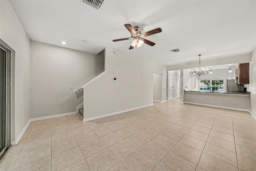 An open-concept living area features light tile flooring, a ceiling fan, and a kitchen pass-through — 1124 HILLHURST DRIVE, WESLEY CHAPEL, FL