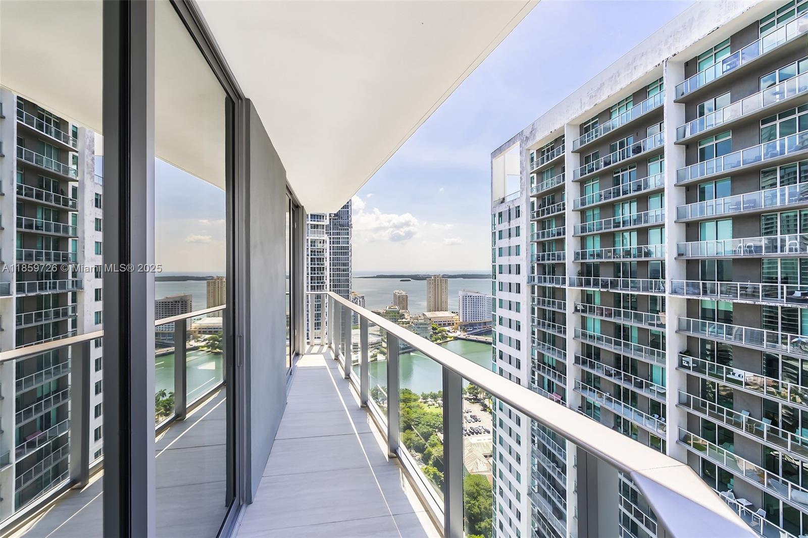 A high-rise balcony with glass railings overlooks a bay and surrounding city buildings — 77 SE 5th St # 2410, Miami FL 33131, MIAMI, FL