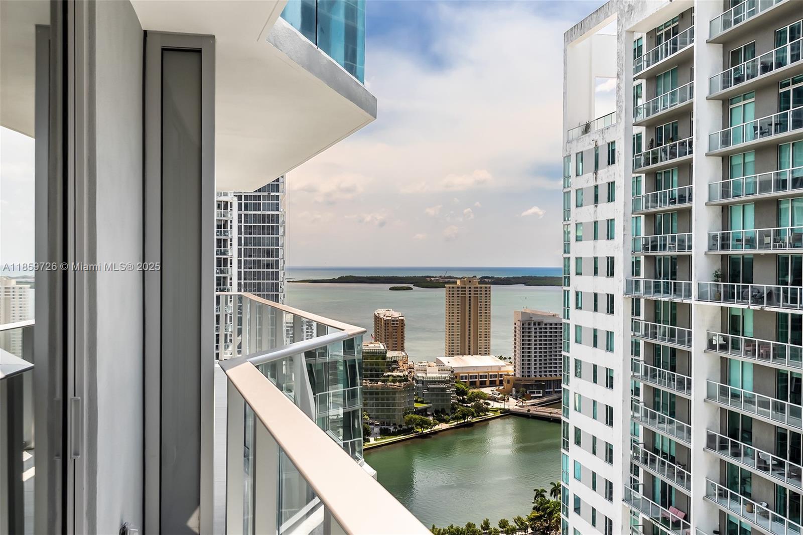 A balcony view overlooks a bay, nearby high-rise buildings, and a distant island — 77 SE 5th St # 2410, Miami FL 33131, MIAMI, FL