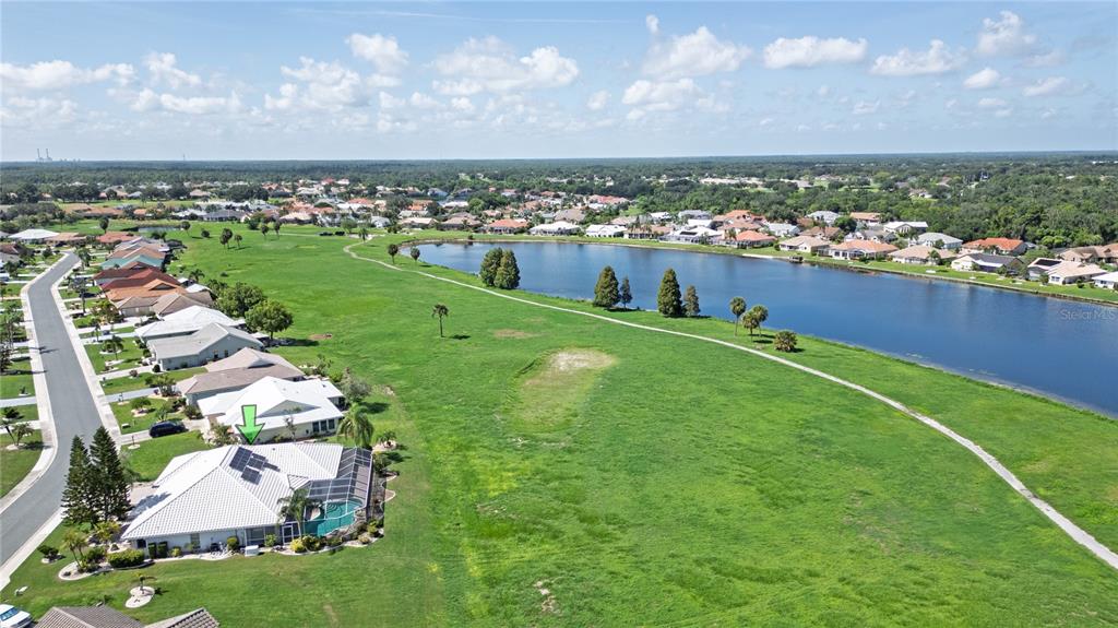 An aerial view shows a residential house with solar panels overlooking a large grassy field — 1936 WOLF LAUREL DRIVE, SUN CITY CENTER, FL