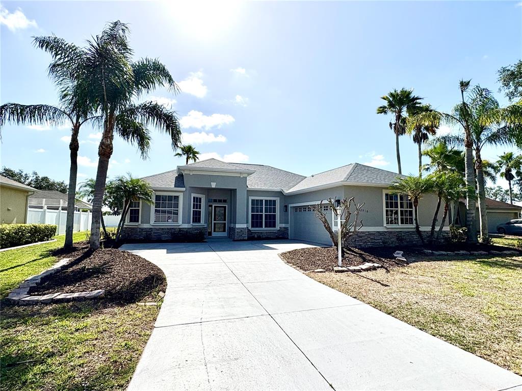 A single-story house with a gray exterior, a concrete driveway, and several palm trees — 2910 122ND TERRACE E, PARRISH, FL