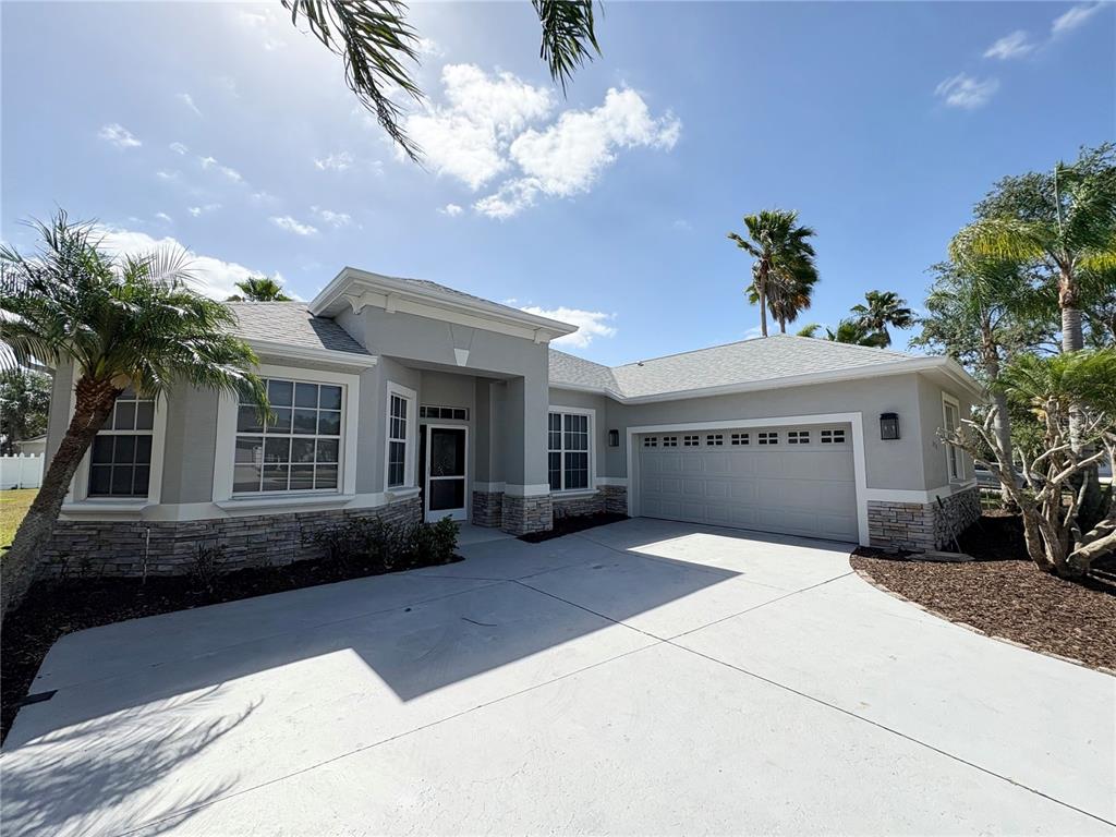 A single-story house with a gray stucco exterior, stone veneer accents, and a two-car garage — 2910 122ND TERRACE E, PARRISH, FL