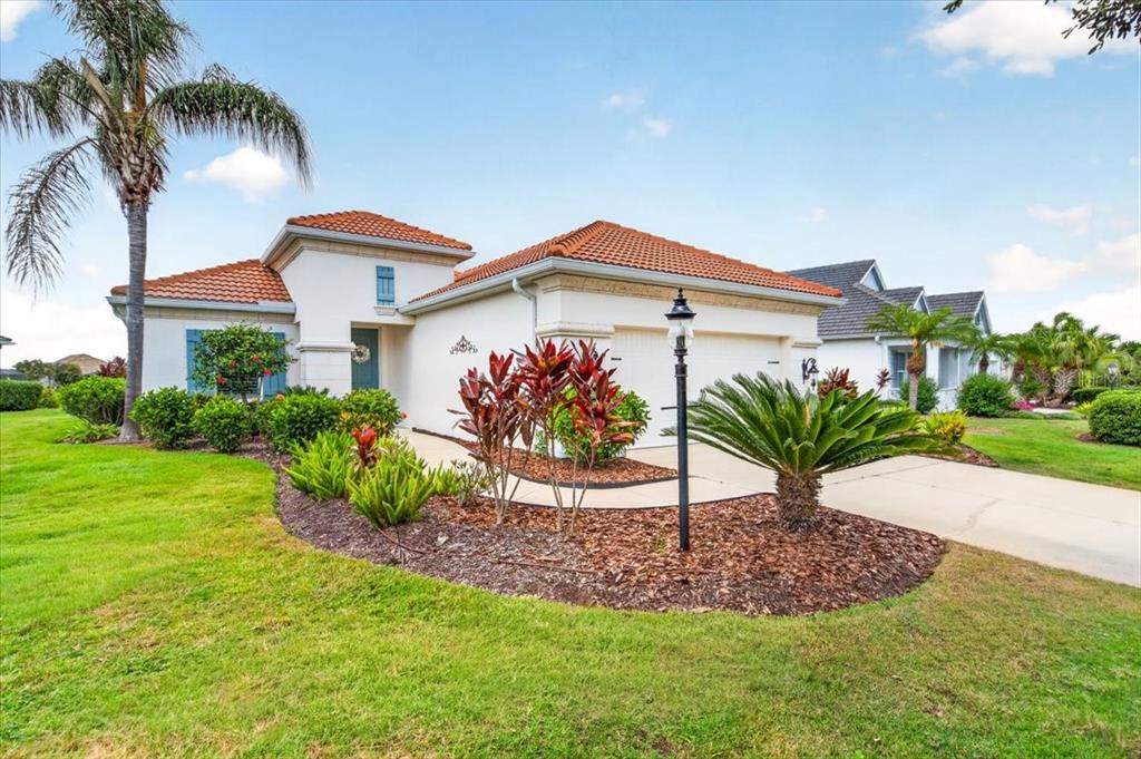 A single-story house with a tiled roof, a palm tree, and a landscaped front yard — 12186 WAKULLA PLACE, VENICE, FL