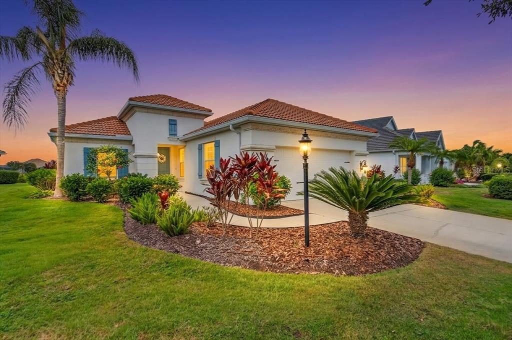 A single-story house with a tile roof, a two-car garage, and landscaped front yard — 12186 WAKULLA PLACE, VENICE, FL