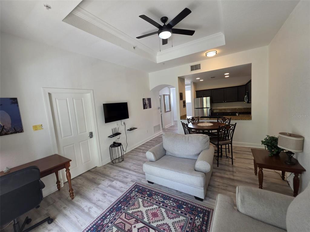 A living room with a tray ceiling, ceiling fan, and an adjacent dining area — 7510 SEVEN EAGLES WAY, REUNION, FL