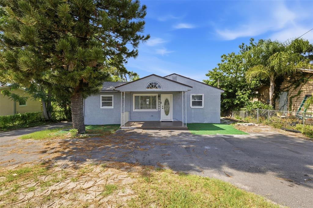 A single-story gray house with a front porch, a large tree, and a paved driveway — 2706 E ANNIE STREET, TAMPA, FL