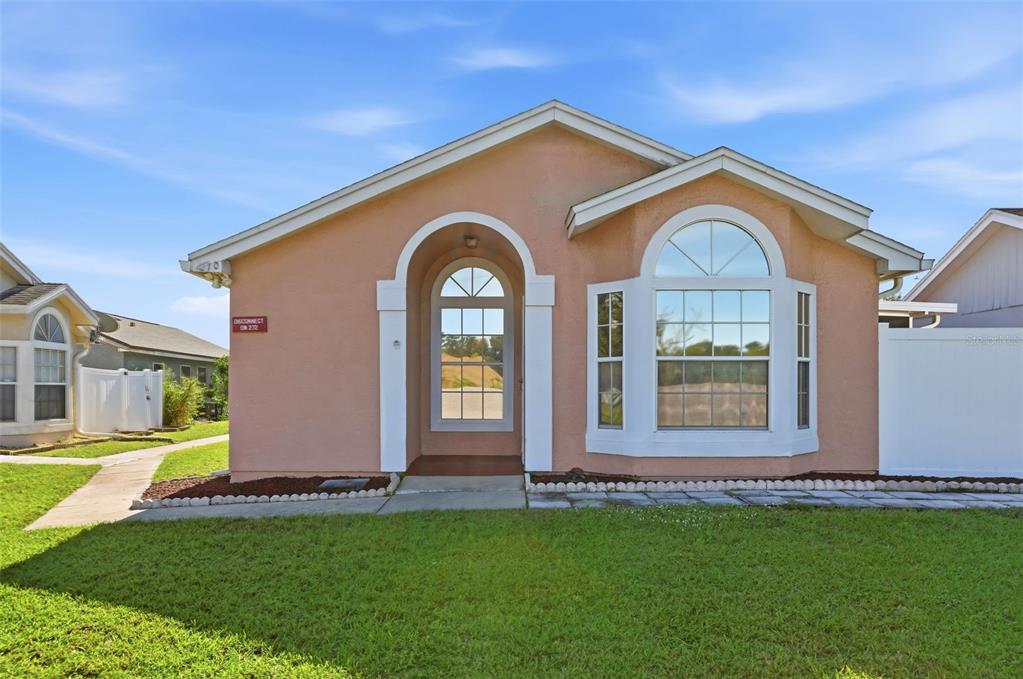 A single-story peach-colored house features an arched entryway and a large bay window — 270 SAN GABRIEL STREET, WINTER SPRINGS, FL