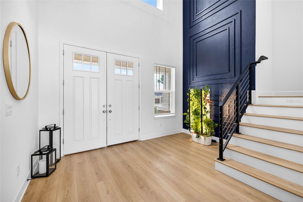 An entryway features light wood floors, a double front door, and a navy accent wall — 6967 TALAMORE DR, WESLEY CHAPEL, FL