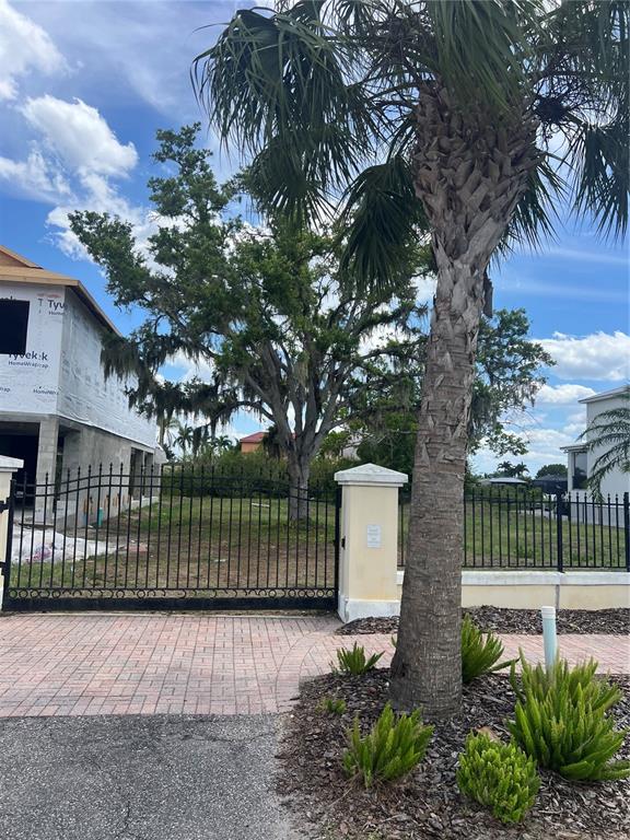 A gated vacant lot sits between two houses with a large palm tree in front — 554 ESTUARY SHORE LANE, APOLLO BEACH, FL