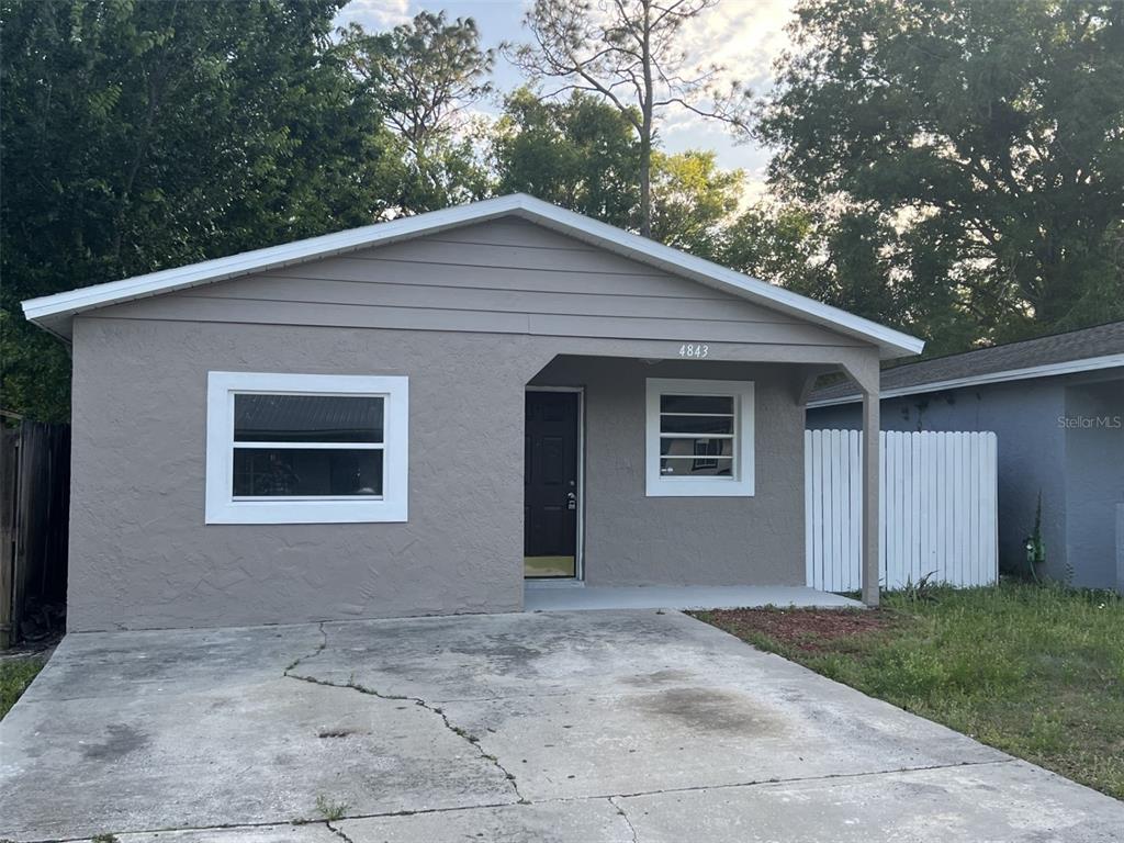 A single-story house with a gray stucco exterior, a concrete driveway, and a white fence — 4843 BILLY DIRECT LANE, LUTZ, FL