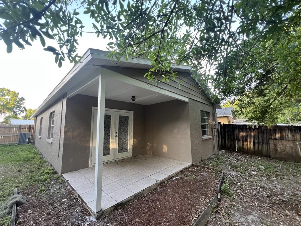 A tan house exterior features a covered patio with tiled flooring and French doors — 4843 BILLY DIRECT LANE, LUTZ, FL