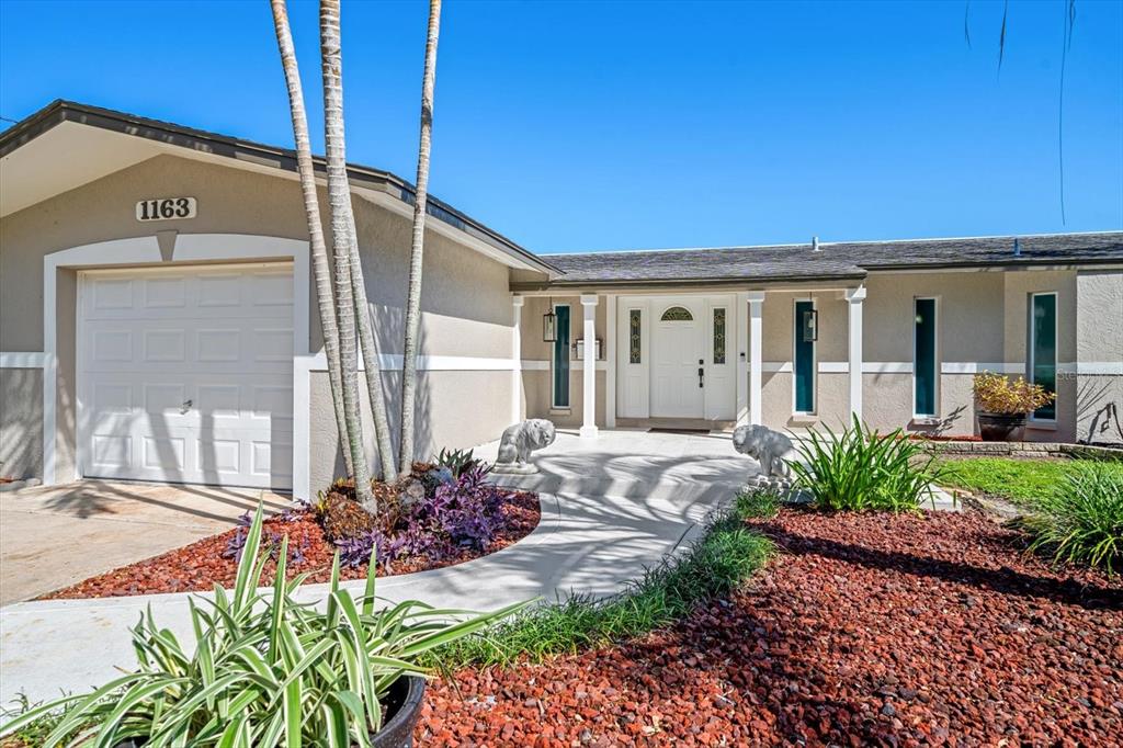 The exterior of a single-story house features a garage, a front entrance, and landscaping — 1163 60TH AVENUE S, ST PETERSBURG, FL