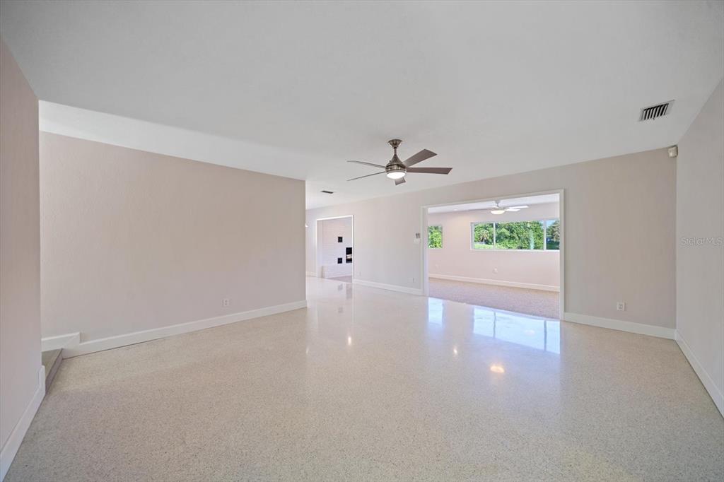A spacious living area features light-colored walls, a ceiling fan, and polished terrazzo flooring — 1163 60TH AVENUE S, ST PETERSBURG, FL