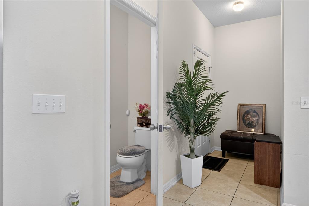A view from a hallway into a small bathroom with a toilet and a potted plant — 9118 SHEPTON STREET, ORLANDO, FL