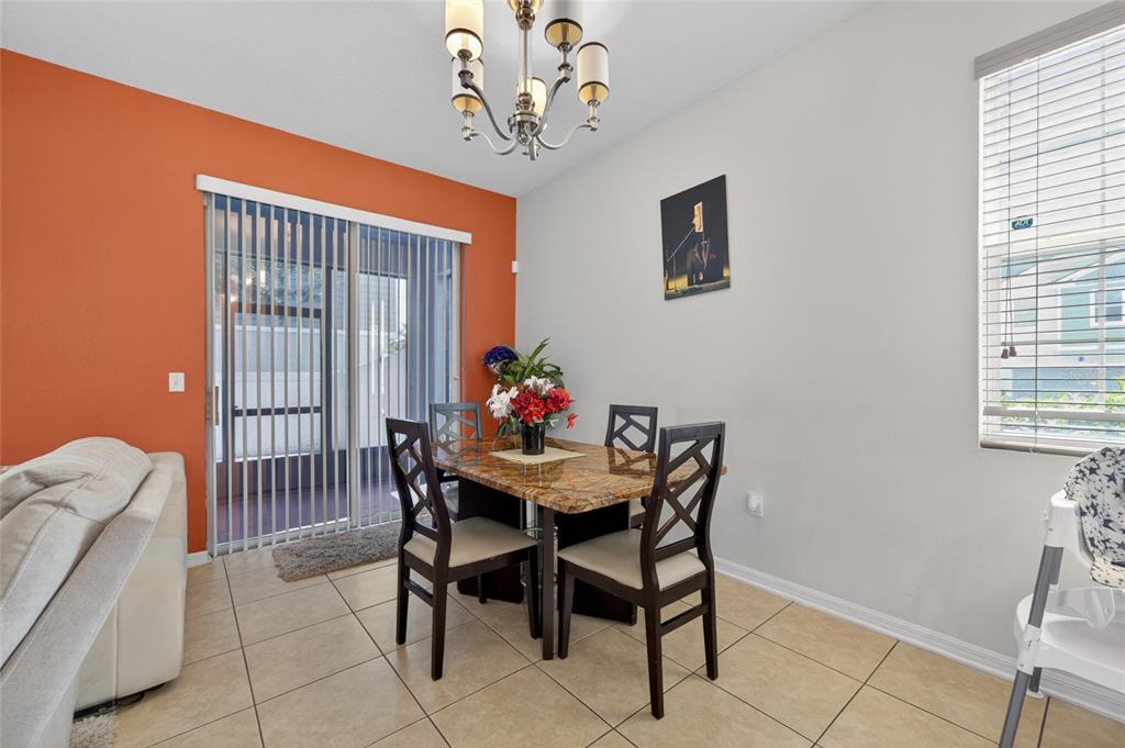 A dining area features a marble-topped table, four chairs, a chandelier, and an orange accent wall — 9118 SHEPTON STREET, ORLANDO, FL
