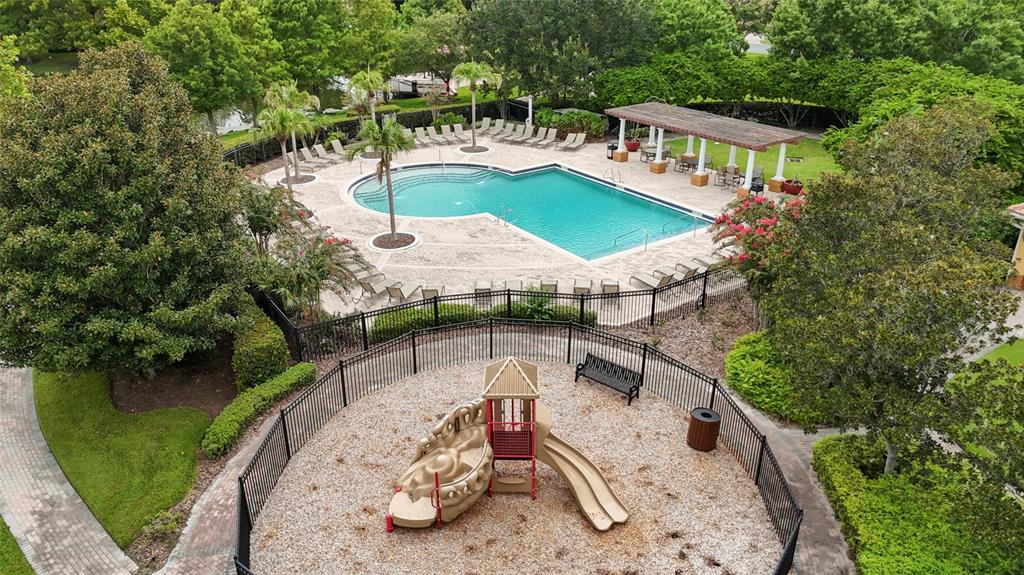 An aerial view shows a fenced playground with a slide next to a community swimming pool — 544 DOUGLAS EDWARD DRIVE, OCOEE, FL
