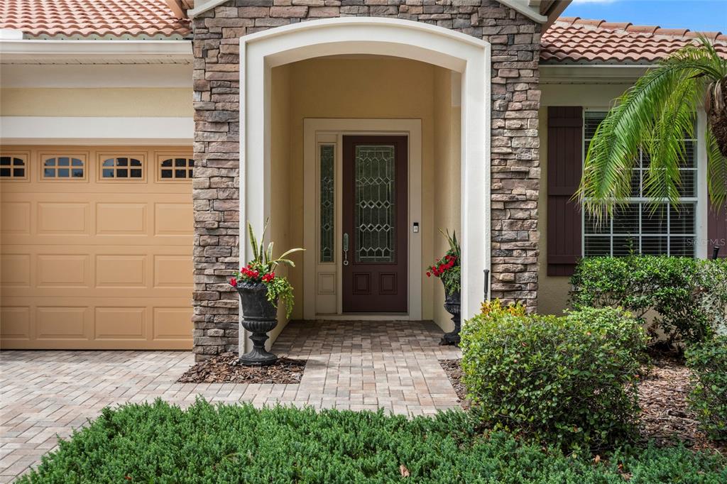The exterior of a house features a stone-accented entryway, a brown front door, and garage — 544 DOUGLAS EDWARD DRIVE, OCOEE, FL