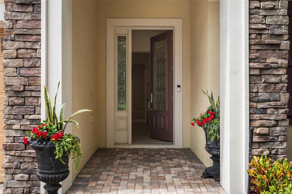 An open front door leads into a home entrance with stone pillars and potted plants — 544 DOUGLAS EDWARD DRIVE, OCOEE, FL