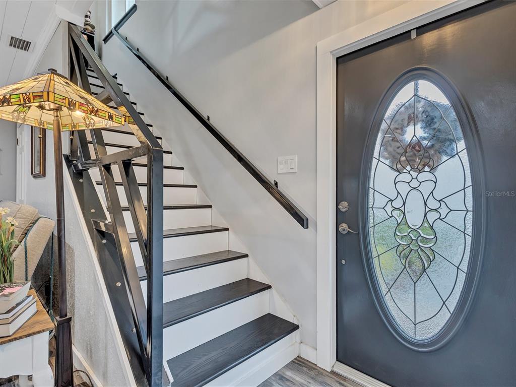 A staircase with dark treads and white risers sits next to a gray front door — 7581 CUMBERLAND ROAD UNIT 7, SEMINOLE, FL