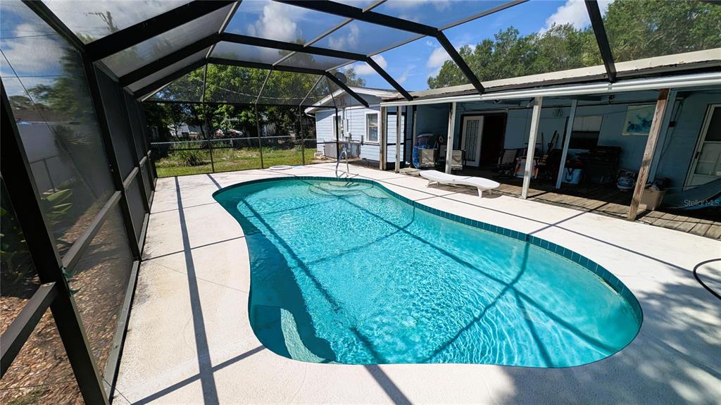 A screened-in patio features a kidney-shaped swimming pool and a white lounge chair — 5350 CASTLEMAN DRIVE, SARASOTA, FL