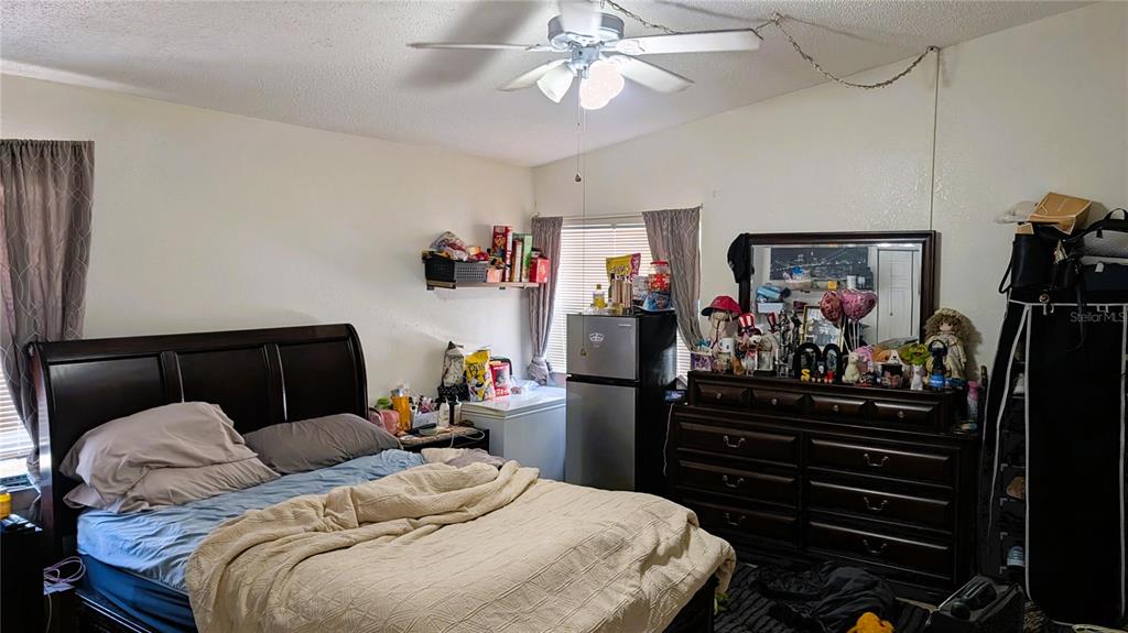 A bedroom features a bed, a dresser with a mirror, and a small refrigerator — 5350 CASTLEMAN DRIVE, SARASOTA, FL