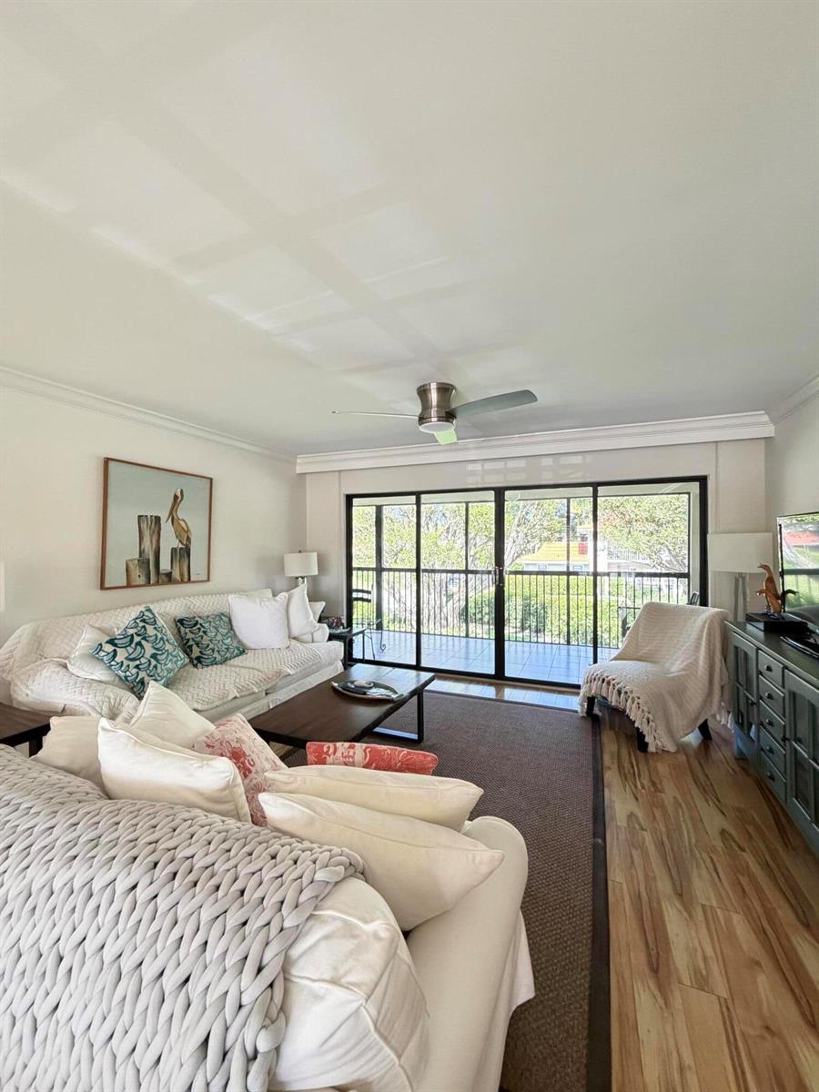 A living room features a white sofa, a coffee table, and sliding glass doors to a balcony — 4607 Kittiwake Court # 2, Boynton Beach FL 33436, BOYNTON BEACH, FL