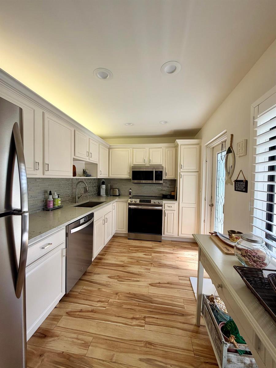 A kitchen with white cabinets, stainless steel appliances, quartz countertops, and wood-look tile flooring — 4607 Kittiwake Court # 2, Boynton Beach FL 33436, BOYNTON BEACH, FL