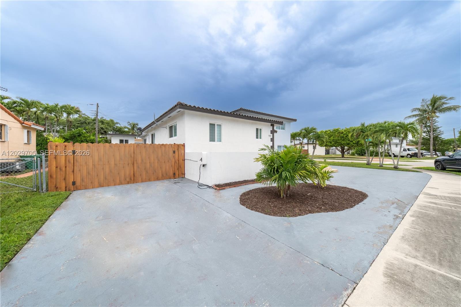 A white house with a wooden fence and a paved driveway featuring a small garden — 1900 SW 83rd Ave, Miami FL 33155, MIAMI, FL
