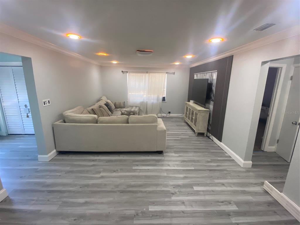 A living room features light gray flooring, a sectional sofa, and a television wall accent — 3303 19TH STREET COURT E, BRADENTON, FL