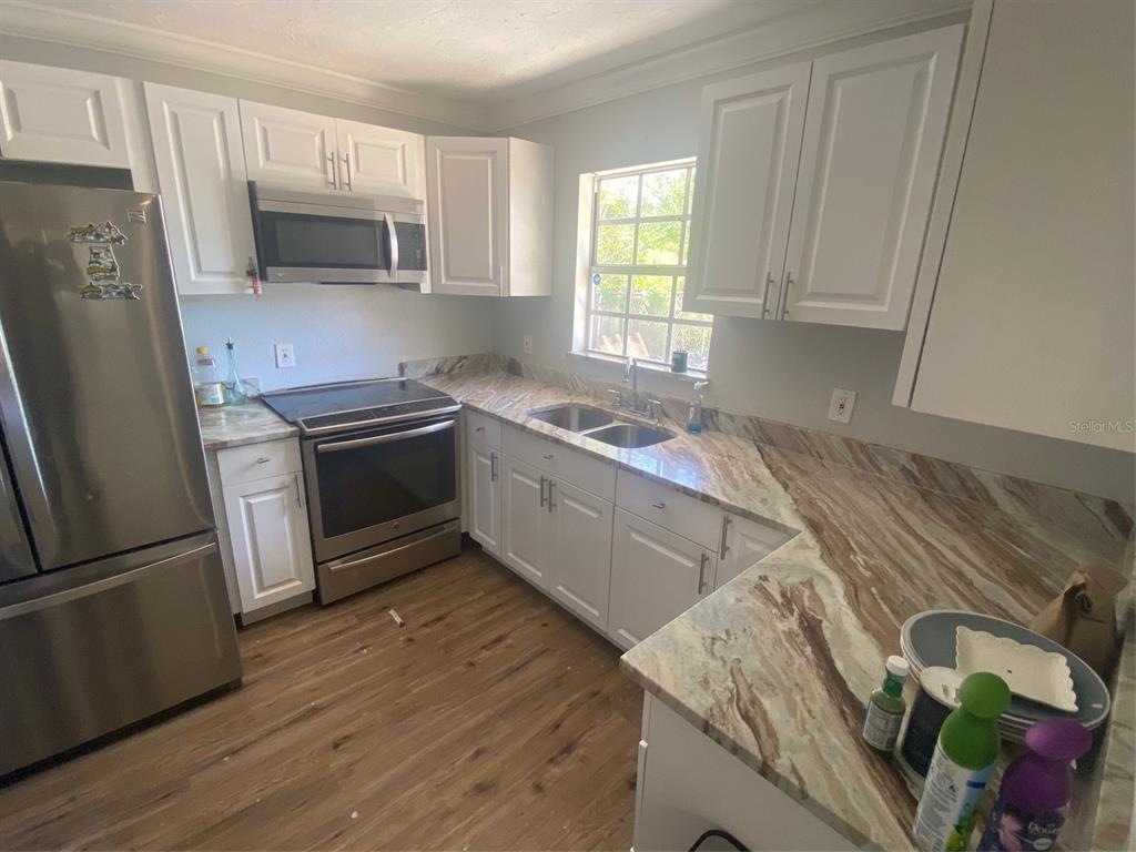 A kitchen features white cabinets, stainless steel appliances, and brown-toned marble-patterned countertops — 3303 19TH STREET COURT E, BRADENTON, FL