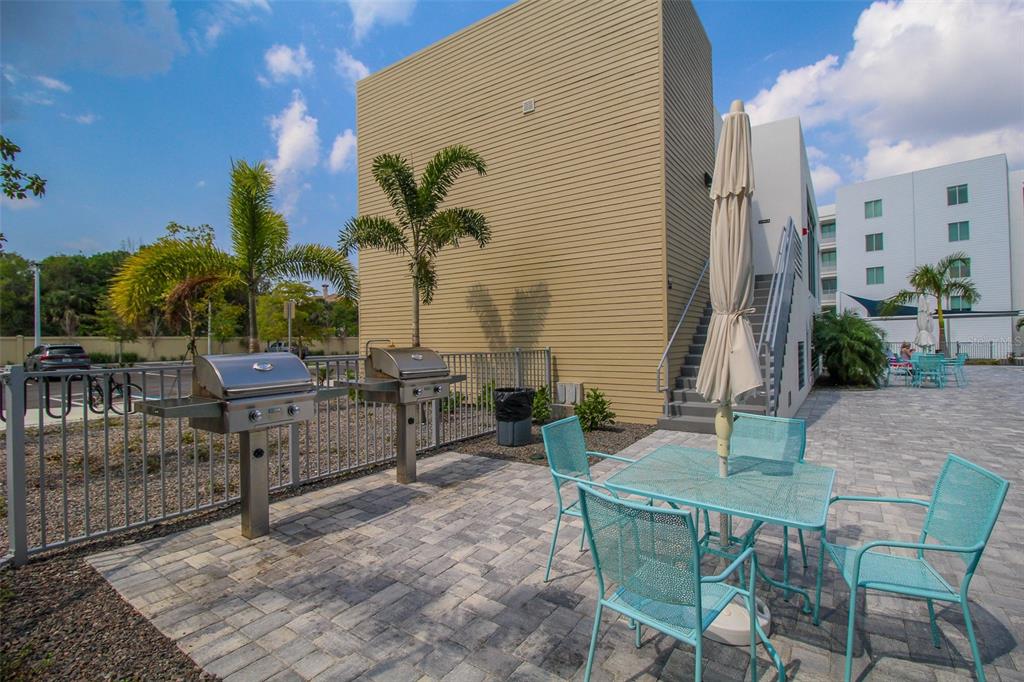 An outdoor patio area features two stainless steel grills, a table with chairs, and stairs — 1703 N TAMIAMI TRAIL UNIT B406, SARASOTA, FL