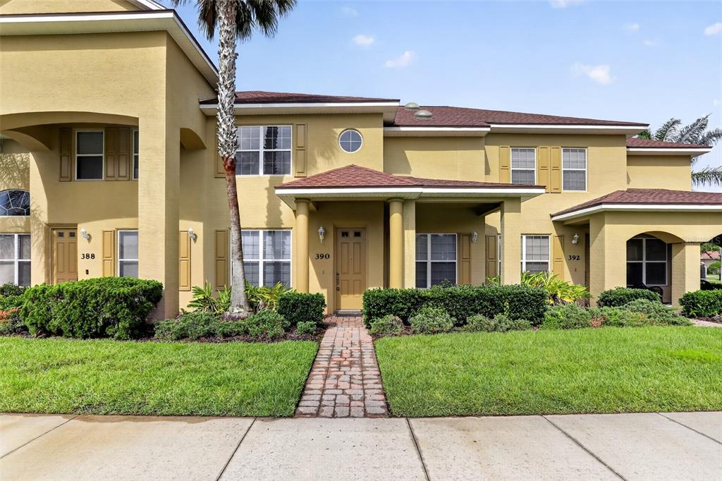 A tan two-story multi-unit building features a brick walkway leading to a central entrance — 390 N AIRPORT ROAD, NEW SMYRNA BEACH, FL