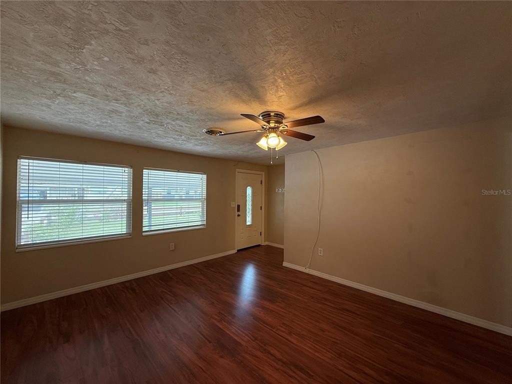 A living room features wood-look flooring, a ceiling fan, and two windows — 438 PERDITA AVENUE, EDGEWATER, FL