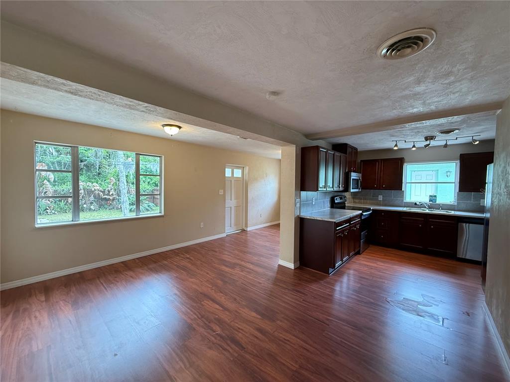An open-concept kitchen and dining area features dark wood cabinets and laminate flooring — 438 PERDITA AVENUE, EDGEWATER, FL