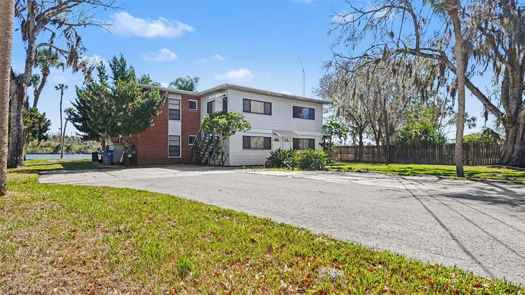 A two-story apartment building with brick and white siding sits beside a paved parking area — 10684 W HALLS RIVER ROAD UNIT 2, HOMOSASSA, FL