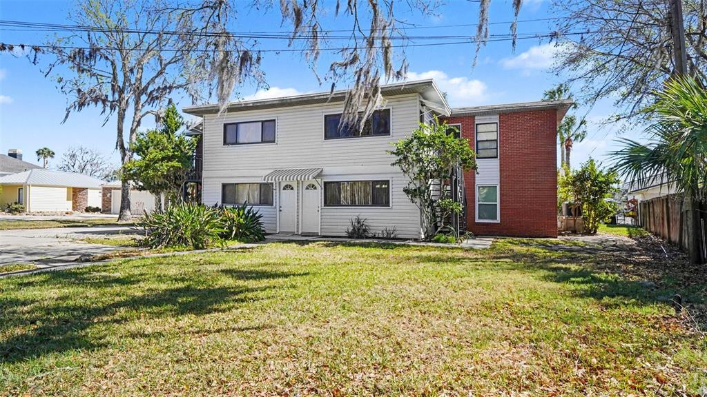 A two-story apartment building with white siding, a red brick section, and a front lawn — 10684 W HALLS RIVER ROAD UNIT 2, HOMOSASSA, FL