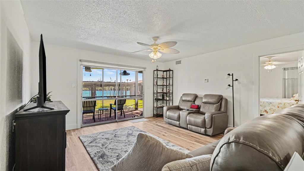 A living room with light wood floors, a ceiling fan, and sliding doors to a patio — 10684 W HALLS RIVER ROAD UNIT 2, HOMOSASSA, FL