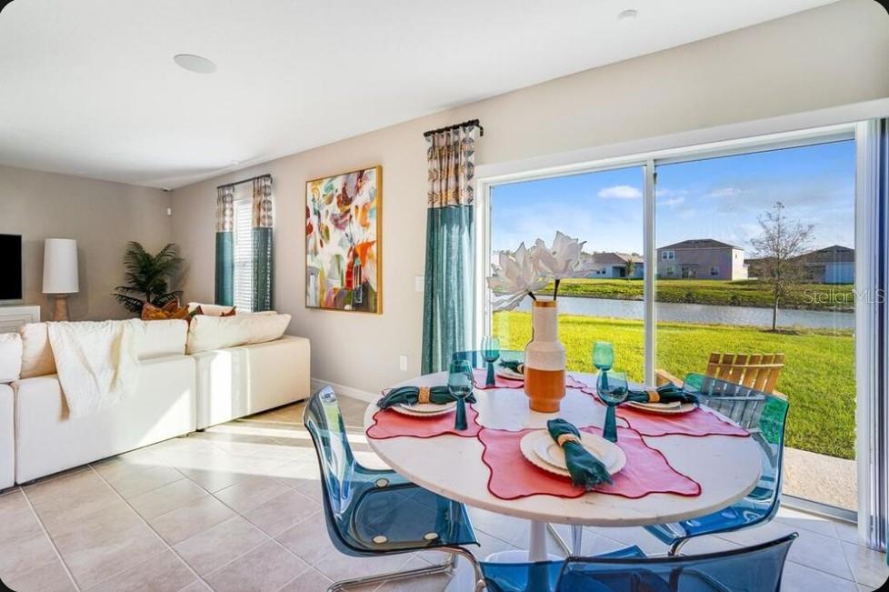 A dining area with a round table and blue chairs overlooks a pond and houses — 6518 EQUINOX LANE, NORTH FORT MYERS, FL