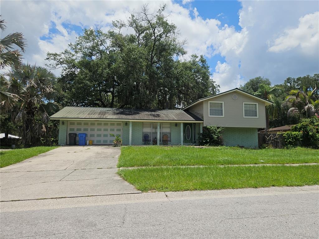 A split-level house with a two-car garage, light green brick, and gray siding — 1203 LAKE VALRICO LANE, VALRICO, FL
