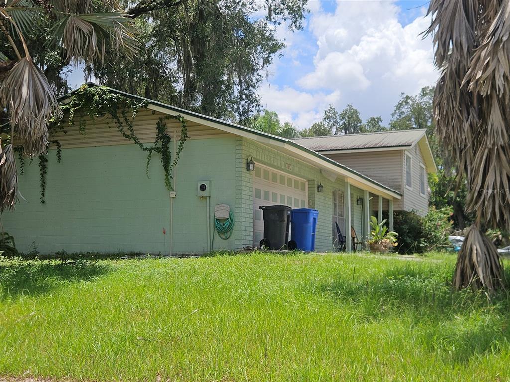 A light green brick house with a garage and a covered porch under a metal roof — 1203 LAKE VALRICO LANE, VALRICO, FL