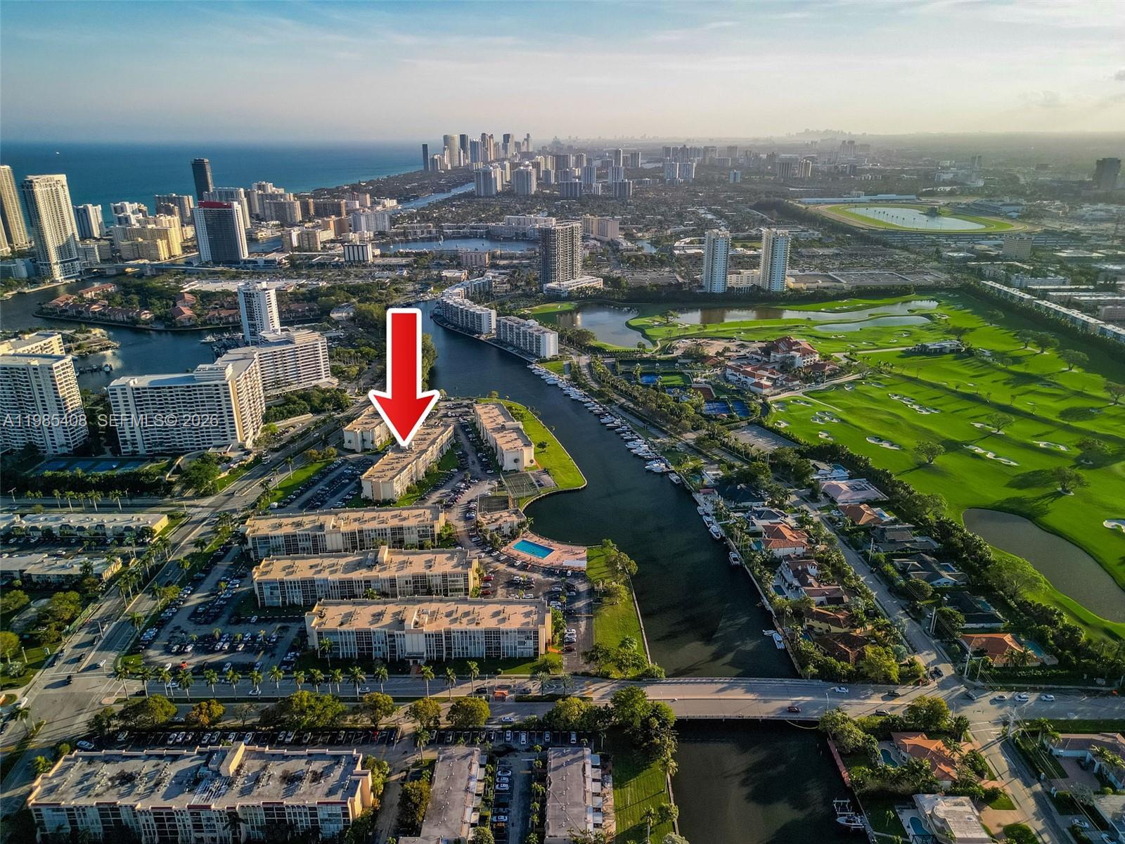 An aerial view shows a multi-story apartment complex situated along a canal near a golf course — 701 Three Islands Blvd # 411, Hallandale Beach FL 33009, HALLANDALE BEACH, FL