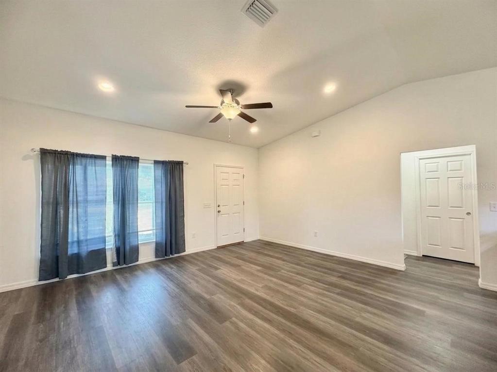 An empty living room features wood-look flooring, a ceiling fan, and a white front door — 48 MAPLE DRIVE, OCKLAWAHA, FL