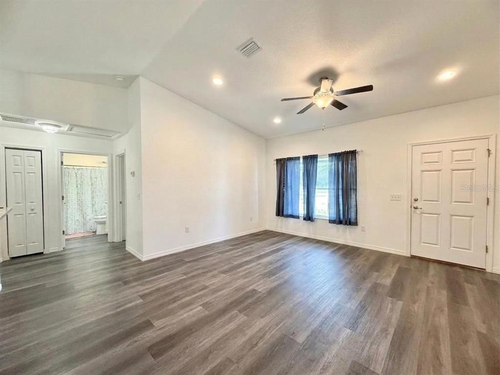 A living room with white walls, wood-look flooring, a ceiling fan, and a front door — 48 MAPLE DRIVE, OCKLAWAHA, FL