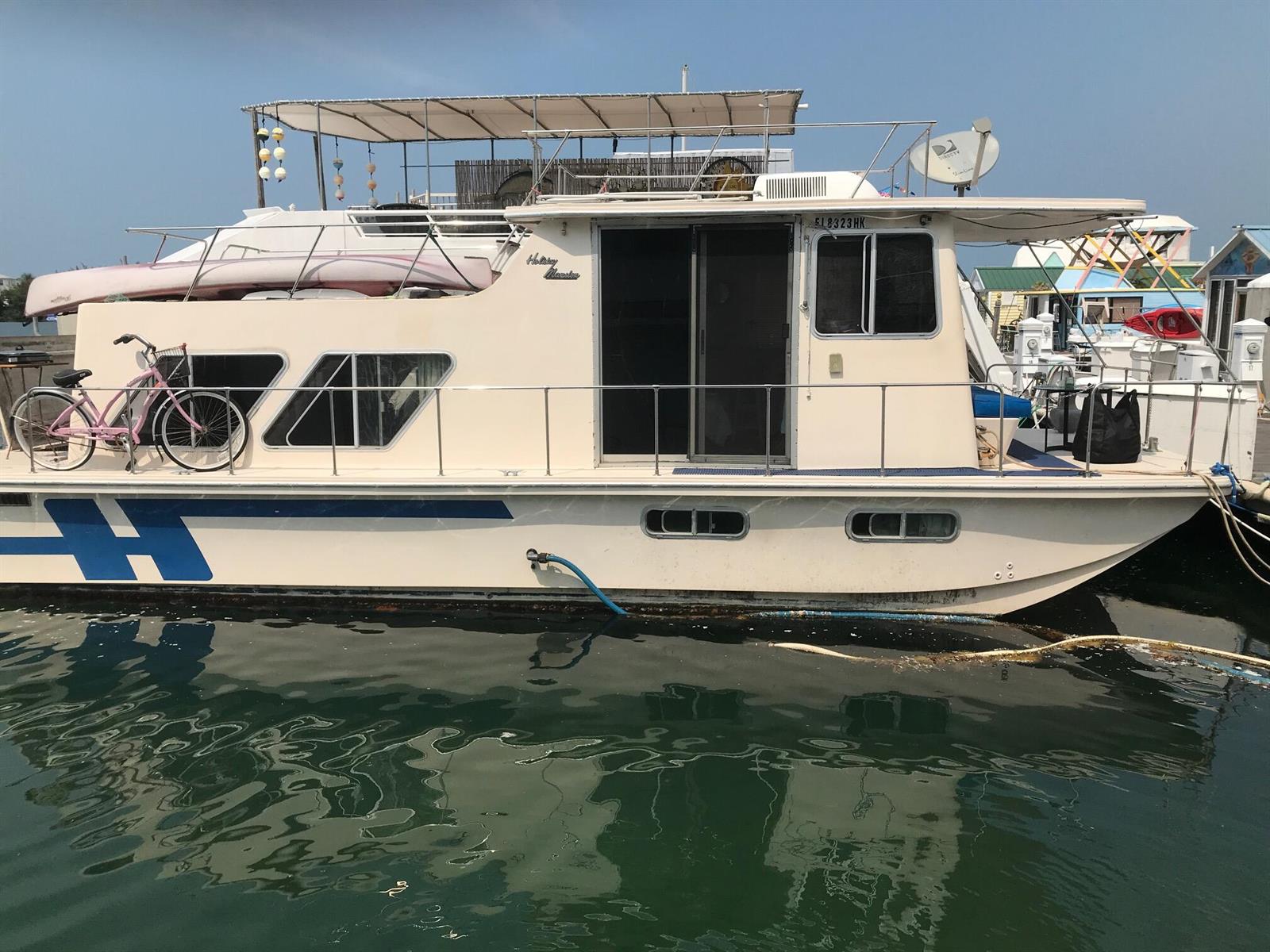 A white houseboat with a pink bicycle docked in the water under a clear sky — 1801 N Roosevelt Boulevard, Key West FL 33040, KEY WEST, FL