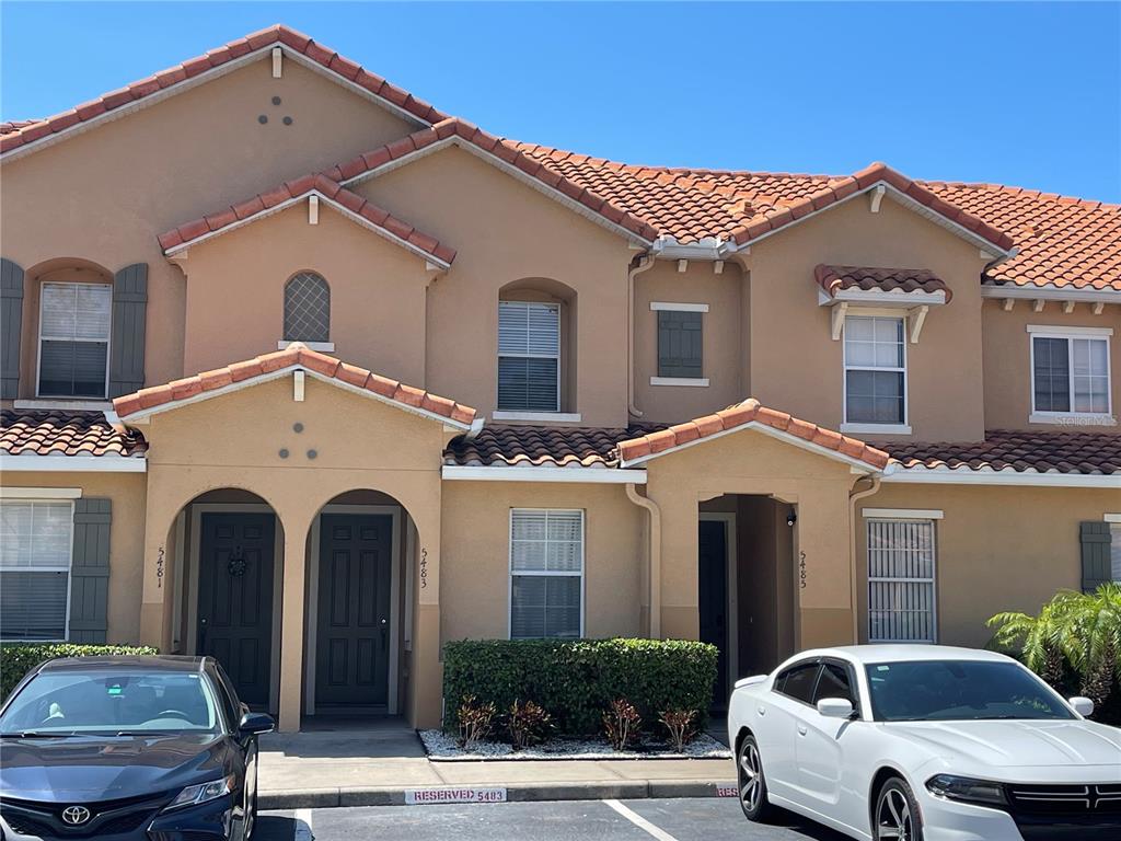 A two-story tan stucco townhouse with a red tile roof and two front entrances — 5483 PARADISE CAY CIRCLE, KISSIMMEE, FL
