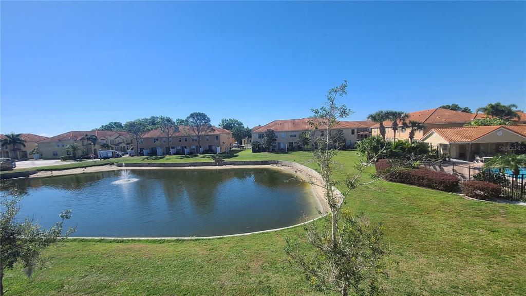 A view of a pond surrounded by multi-story residential buildings and green lawn — 5483 PARADISE CAY CIRCLE, KISSIMMEE, FL
