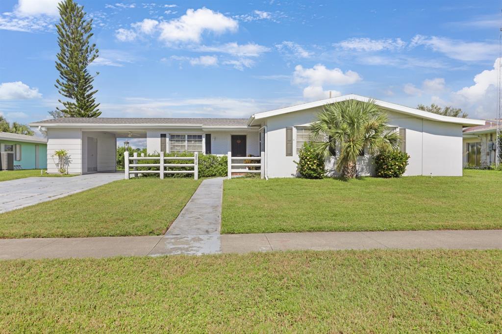 A single-story white house with a carport, a front lawn, and a concrete walkway — 2219 BEACON DRIVE, PORT CHARLOTTE, FL