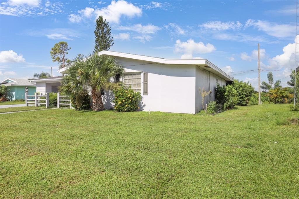 A single-story house with a white exterior, a palm tree, and a grassy yard — 2219 BEACON DRIVE, PORT CHARLOTTE, FL